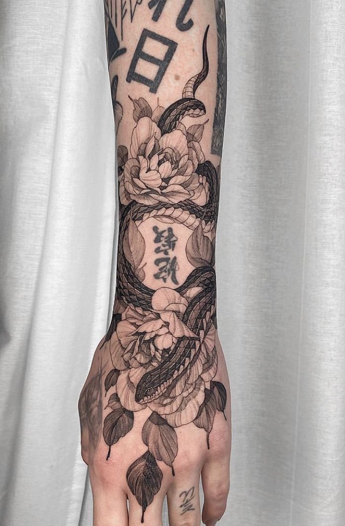 a person's hand with tattoos on it and flowers in the middle of their arm