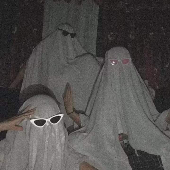 two people in white ghost costumes with sunglasses on their heads and one person wearing glasses covering her face