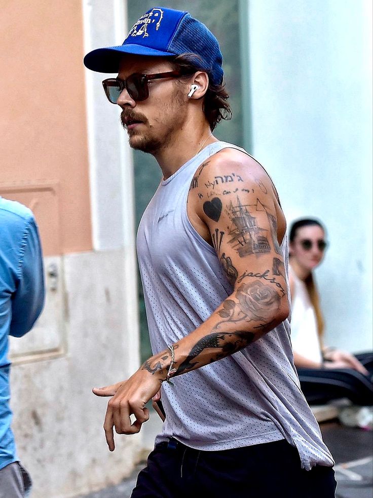 a man with tattoos on his arm walking down the street in front of some people