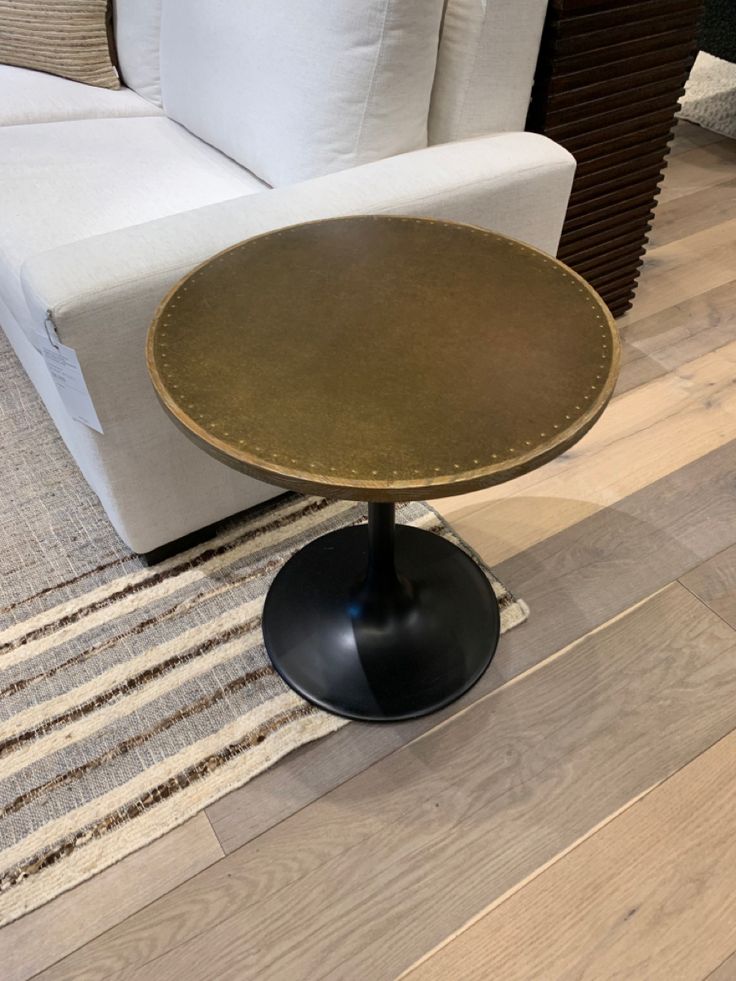 a white couch sitting next to a wooden table on top of a hard wood floor