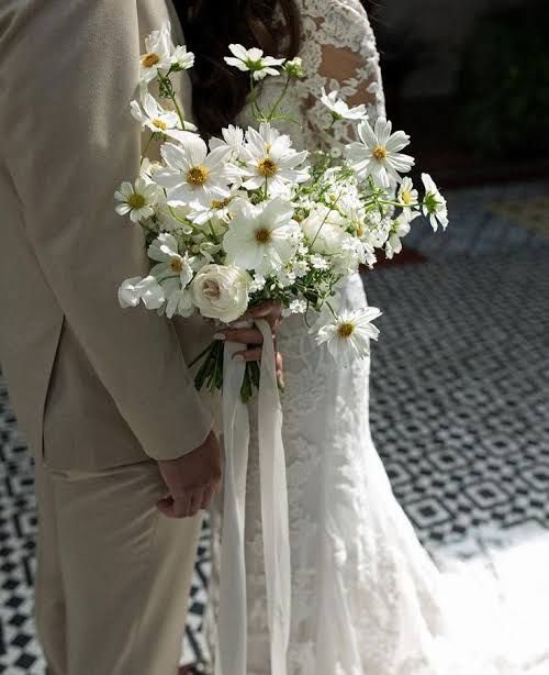 the bride and groom are holding bouquets of white flowers