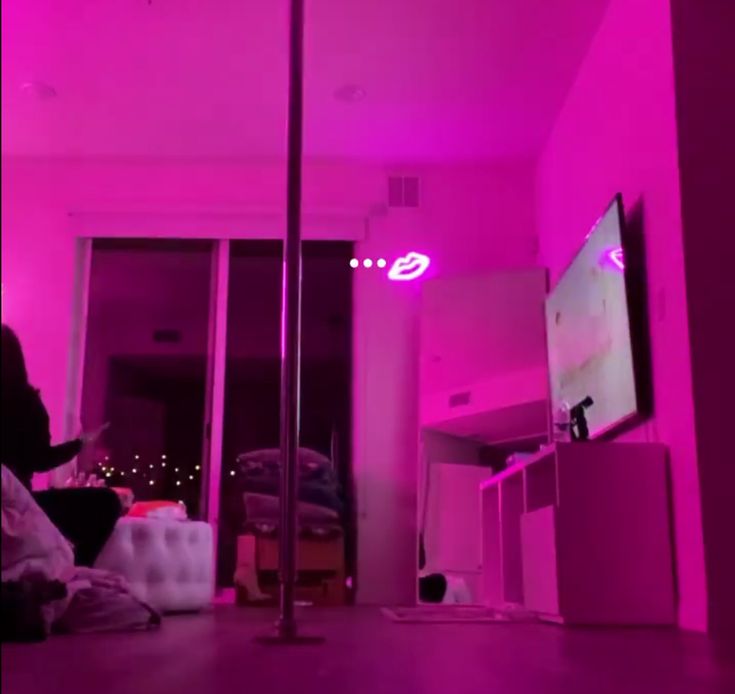 a person sitting in front of a tv on top of a hard wood floor next to a pink wall