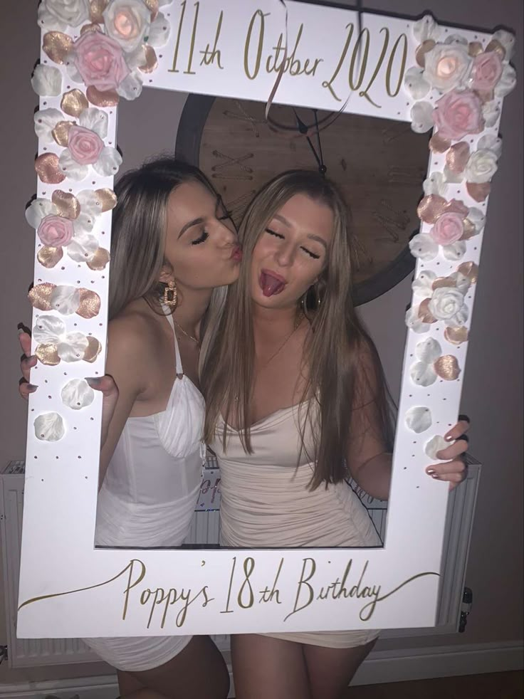 two beautiful young women standing next to each other in front of a birthday photo frame