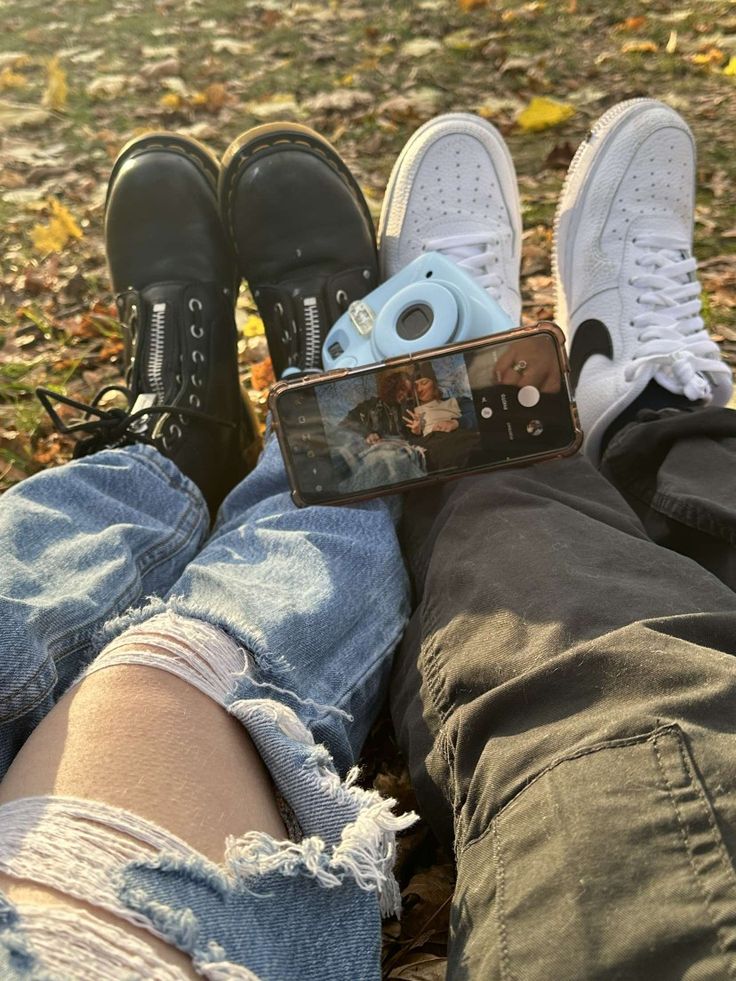 two people sitting on the ground with their legs crossed and one person holding a camera