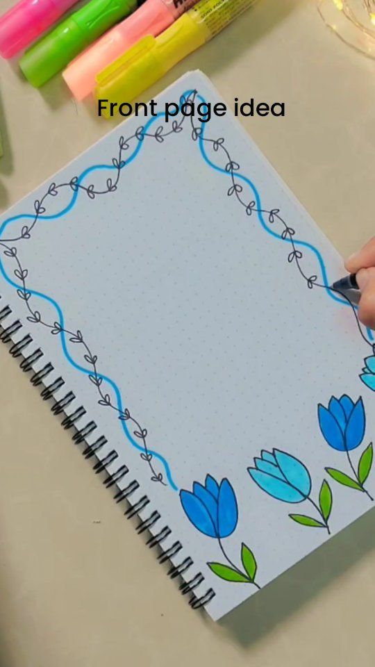 a person is drawing on a notebook with markers