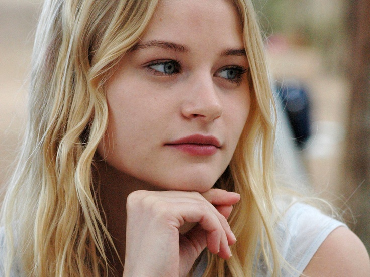 a close up of a person with long blonde hair and blue eyes looking at the camera