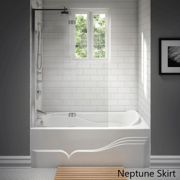 a white bath tub sitting in a bathroom next to a wooden table and framed pictures