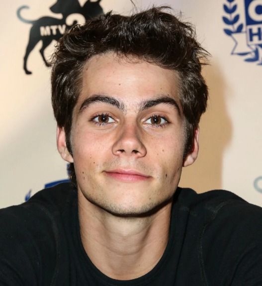 a close up of a person wearing a black shirt and looking at the camera with a serious look on his face