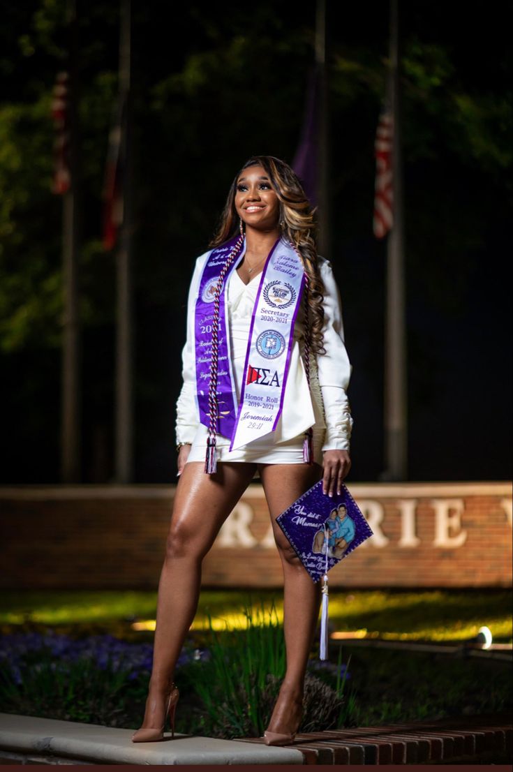 a woman wearing a purple sash standing in front of a sign with flags on it