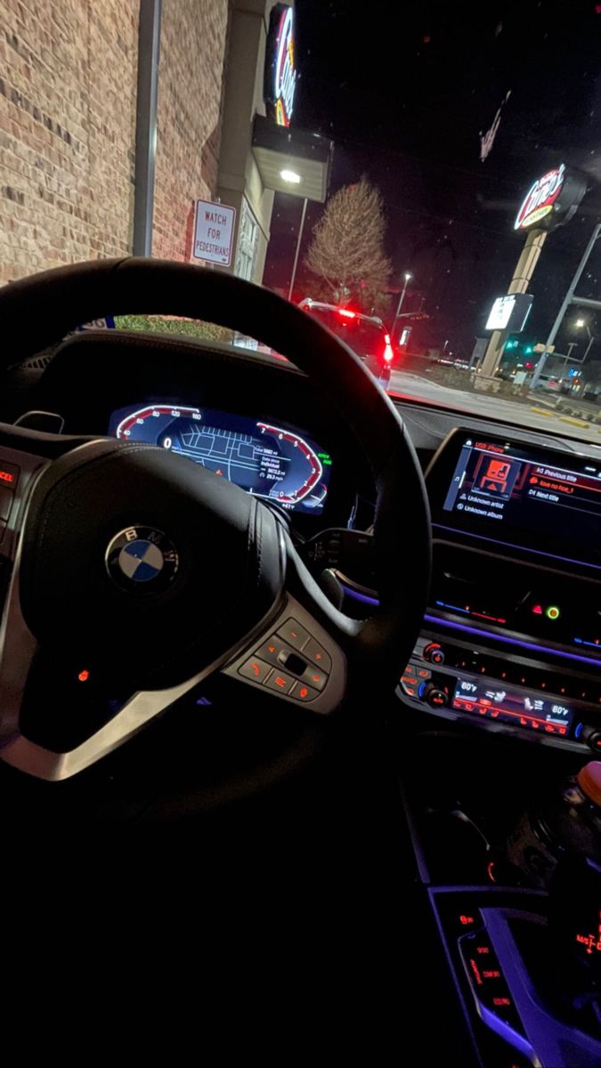 the interior of a car is lit up at night with street lights in the background