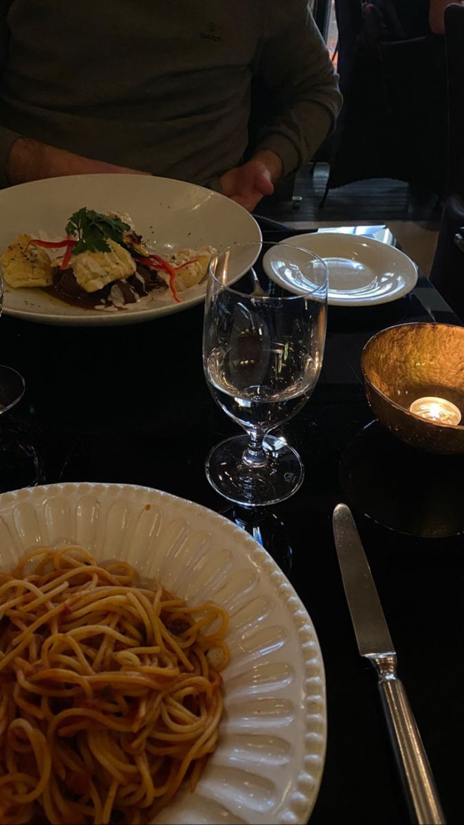 a table topped with plates of food next to wine glasses and utensils on top of a black counter