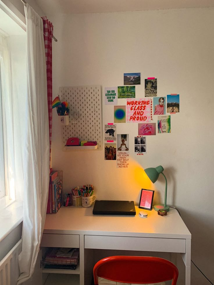 a white desk topped with a laptop computer next to a window covered in pictures on the wall