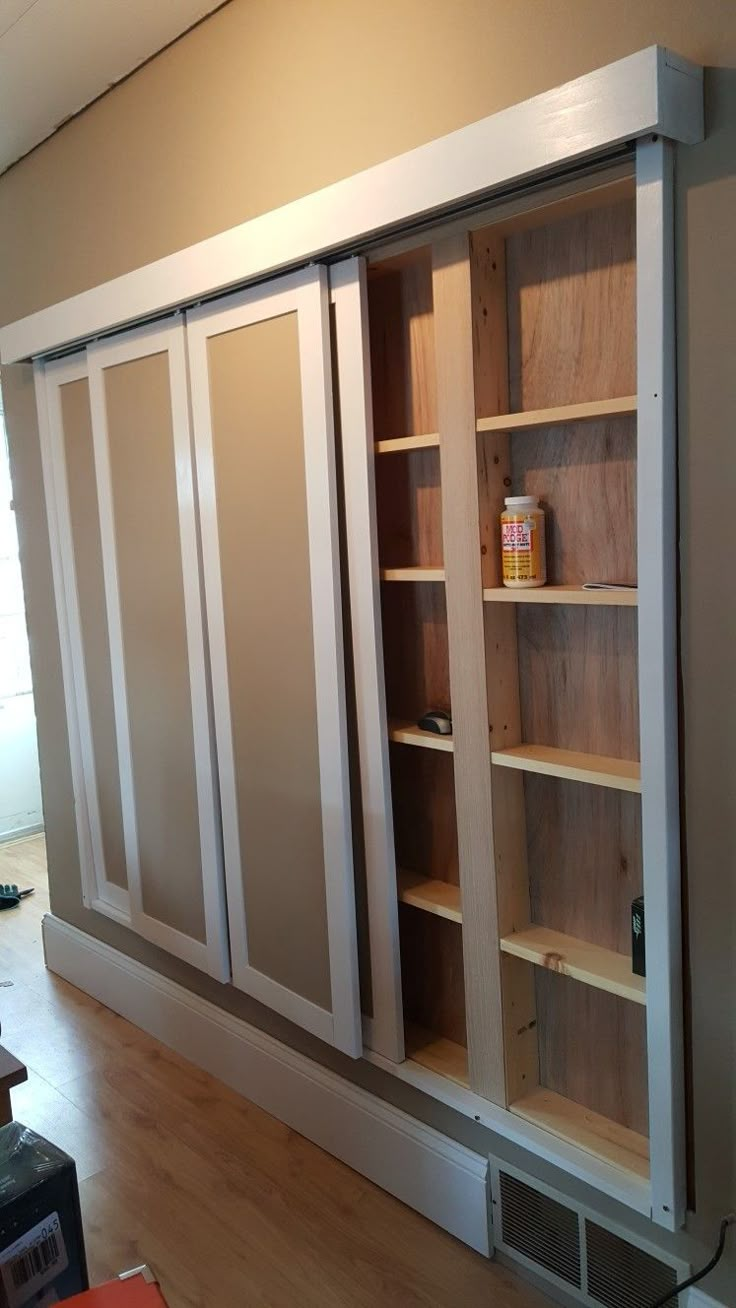 an empty room with wooden shelves and sliding doors on the wall, next to a hard wood floor