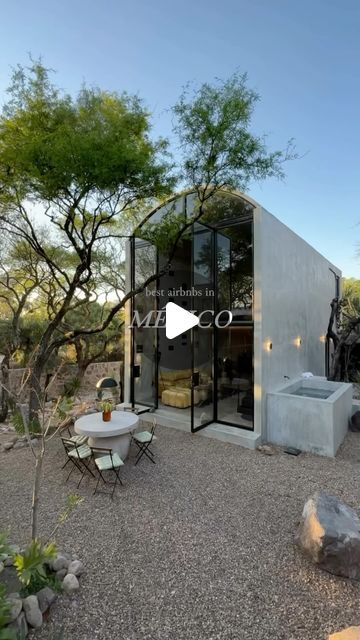 the exterior of a modern home with an outdoor kitchen and dining area in the foreground