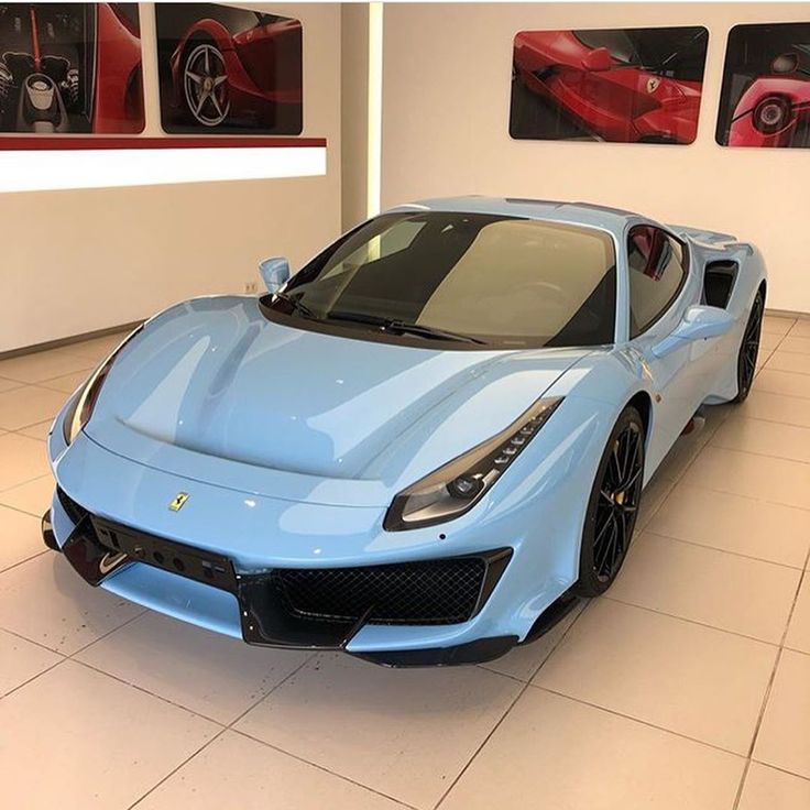 a blue sports car in a showroom with pictures on the wall and floor behind it