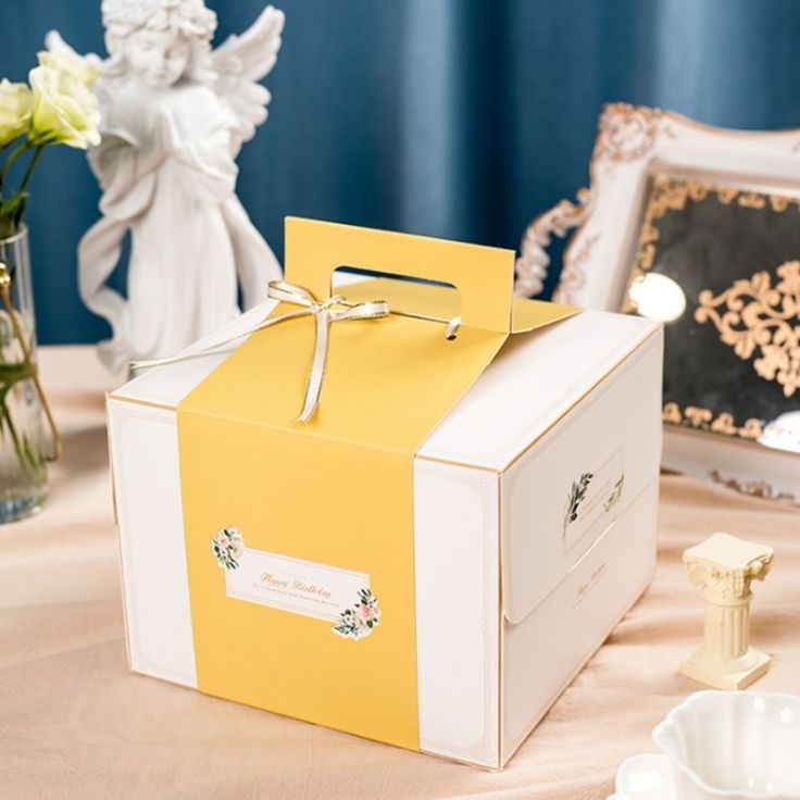 a yellow and white box sitting on top of a table next to some vases