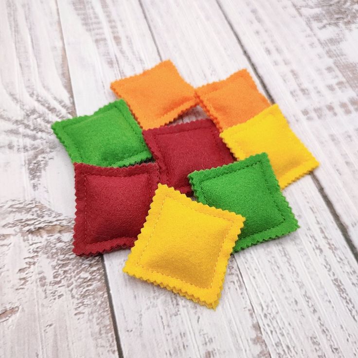 four different colored felt squares sitting on top of a white wooden floor next to each other