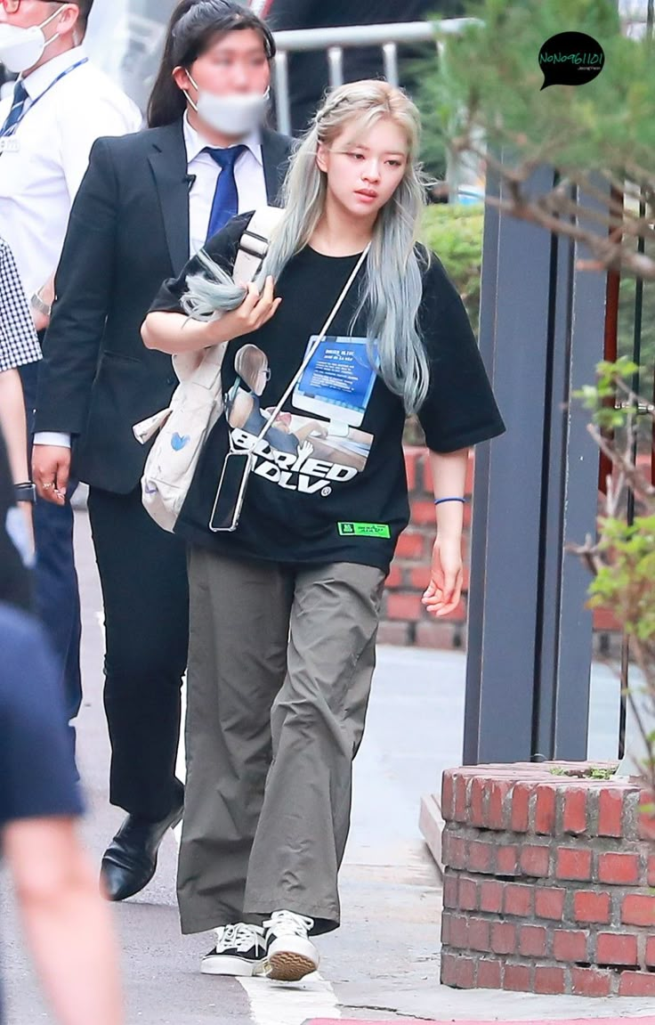 a woman with grey hair walking down the street while wearing a black t - shirt