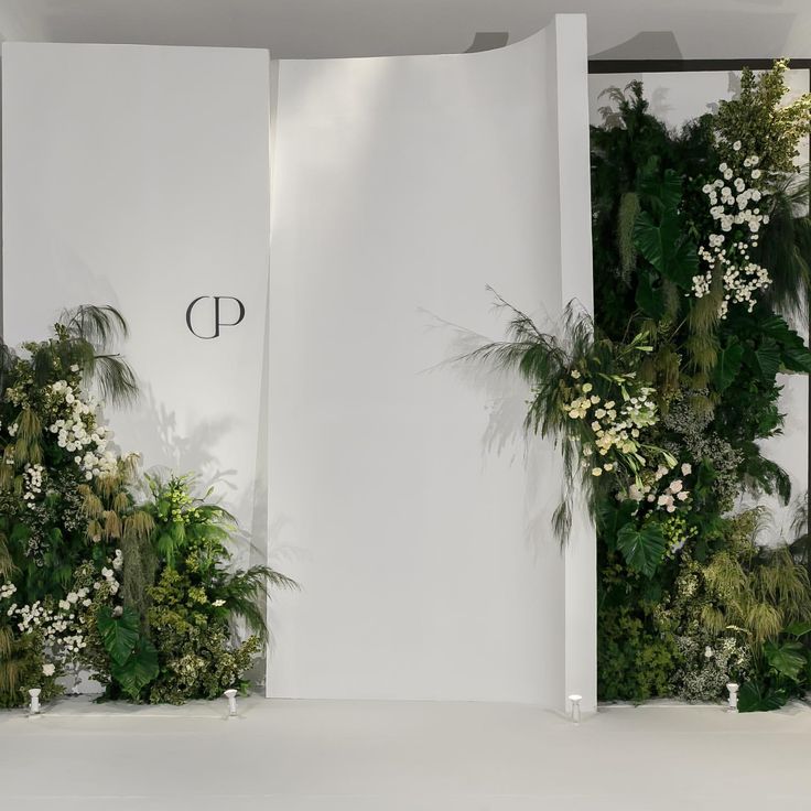 two white walls covered in plants and greenery with the letters p on it's side