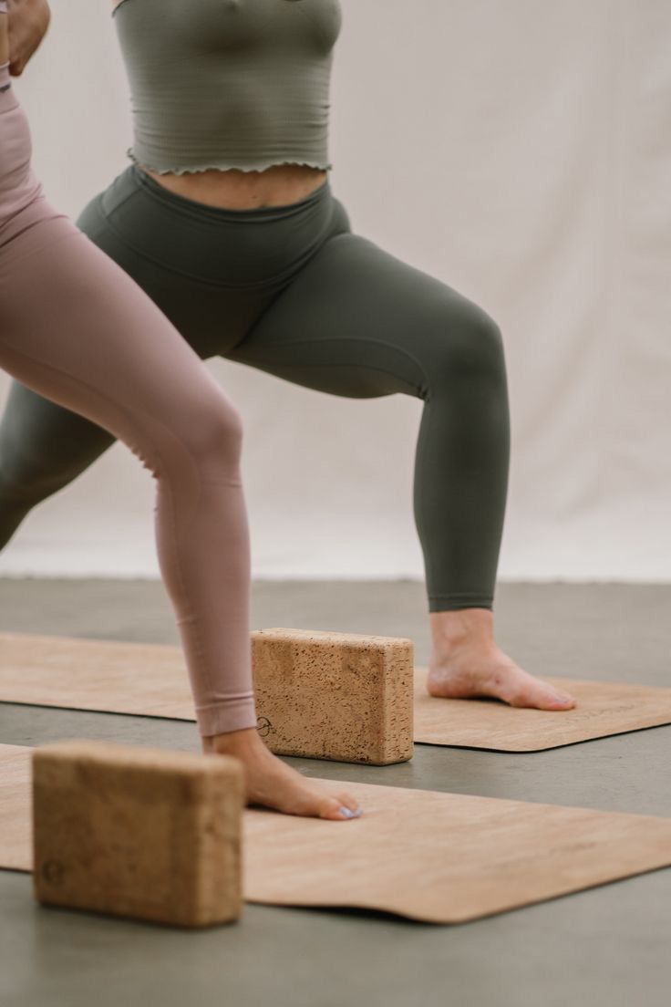 two women doing yoga poses on wooden blocks