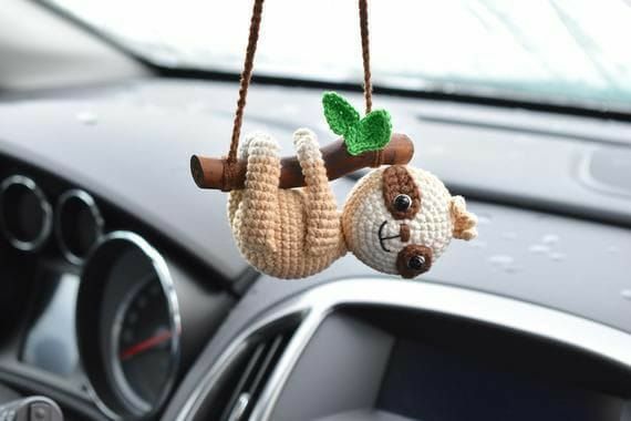 two stuffed animals hanging from a tree in a car's dash board holder with steering wheel controls