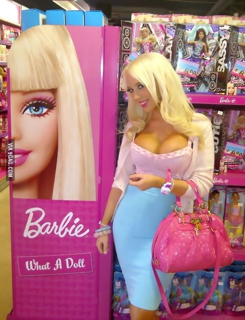 a barbie doll is standing in front of a barbie sign and holding a pink handbag