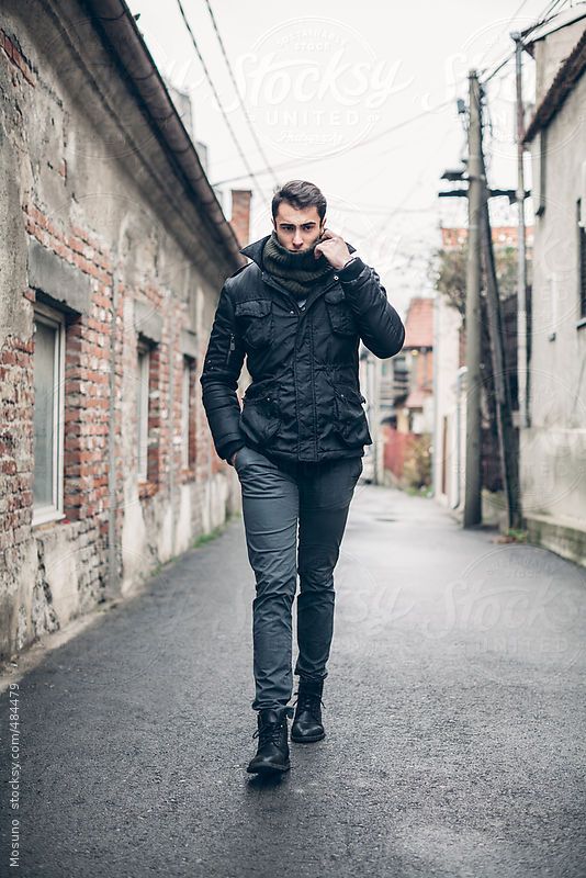 a man is walking down the street talking on his cell phone by an alleyway