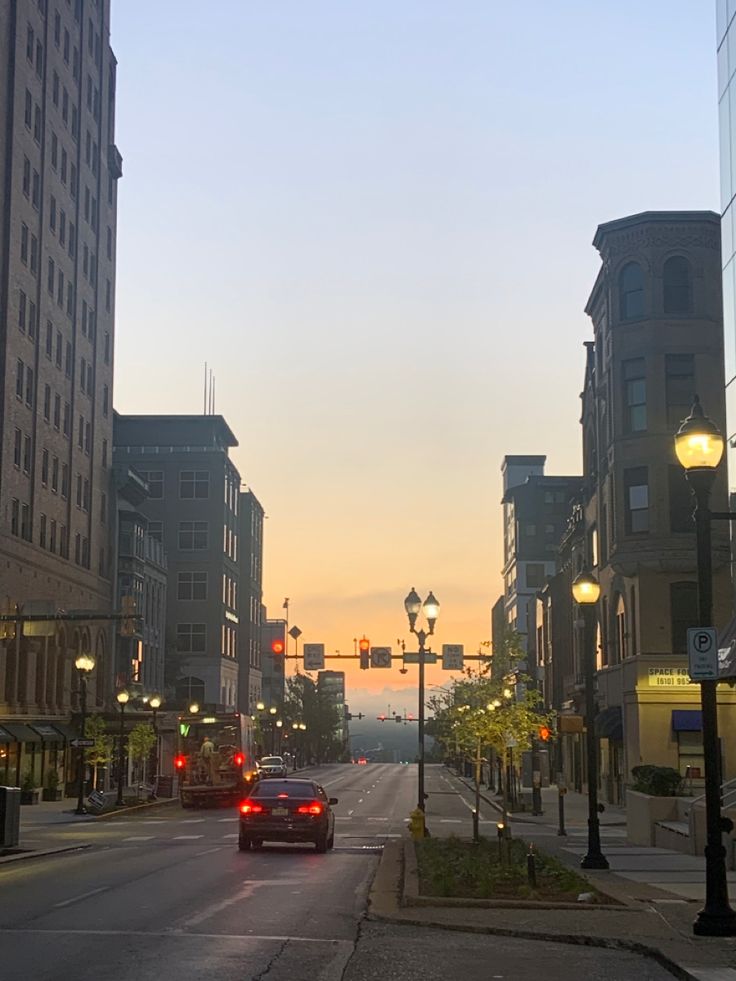 a car is driving down the street in front of some buildings at sunset or dawn