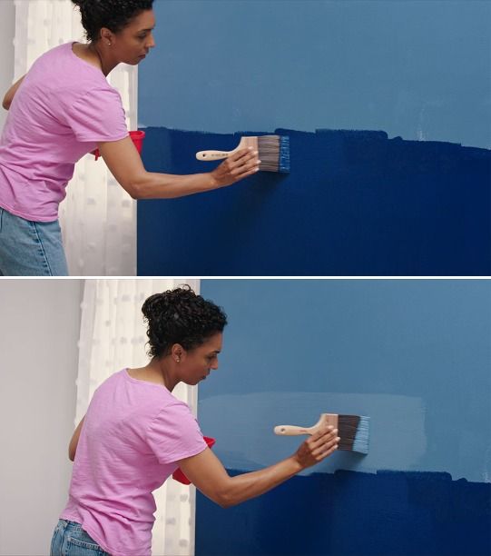 a woman is painting the wall with blue paint and she has a brush in her hand