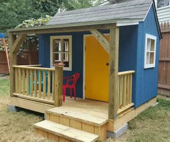 a small blue and yellow shed with steps leading up to the front door that has a red chair on it