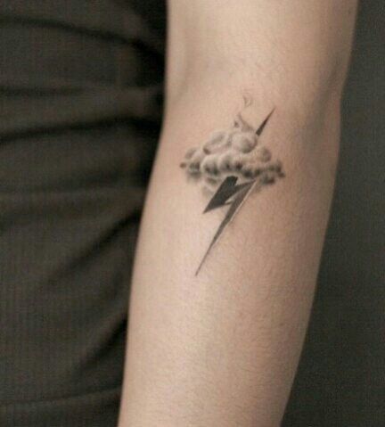 a woman's arm with a lightning and cloud tattoo on it