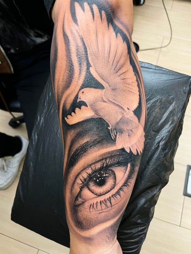 a man's arm with an eye and bird on it