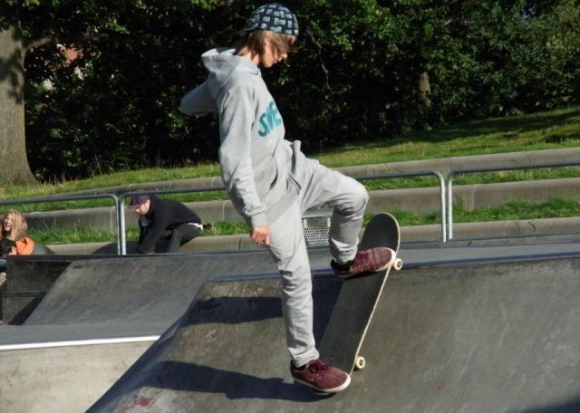 a young man riding a skateboard up the side of a ramp at a skate park