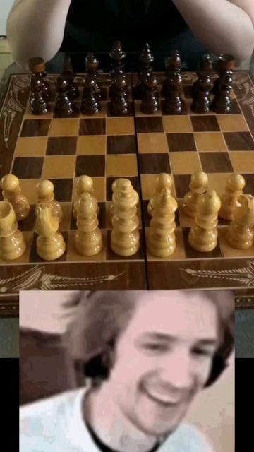 a man sitting at a table next to a giant chess board with the same image on it