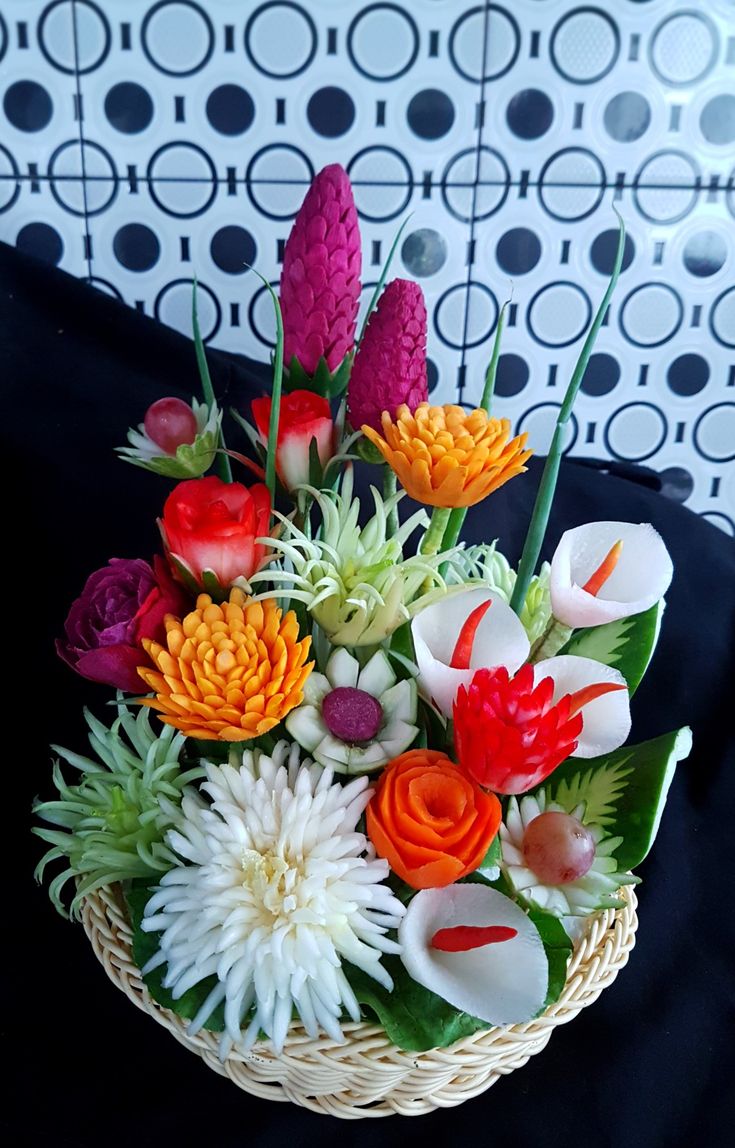 a basket filled with lots of colorful flowers on top of a black cloth covered table