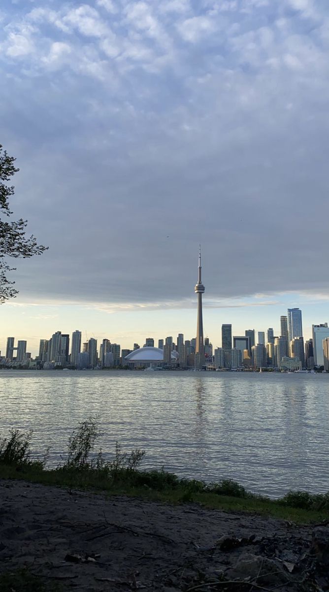 a view of the city skyline from across the water at dusk, with clouds in the sky