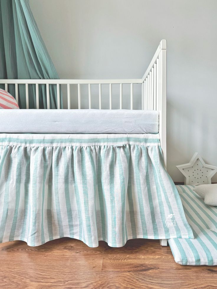 a white crib with a blue and white striped bed skirt