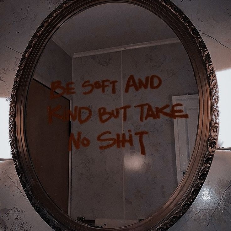 a mirror with graffiti written on it in a bathroom next to a toilet paper dispenser