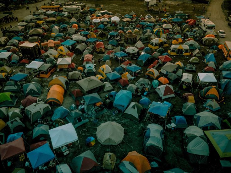 a large group of tents are set up on the ground in front of a dirt road