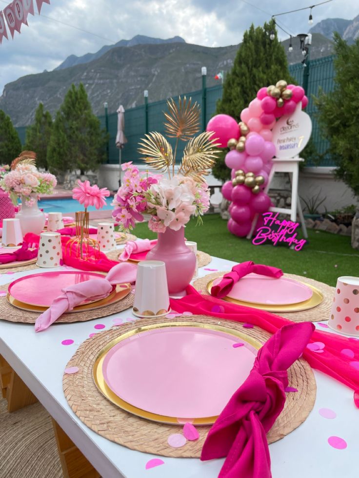 a table set up for a birthday party with pink and gold plates, napkins, and decorations