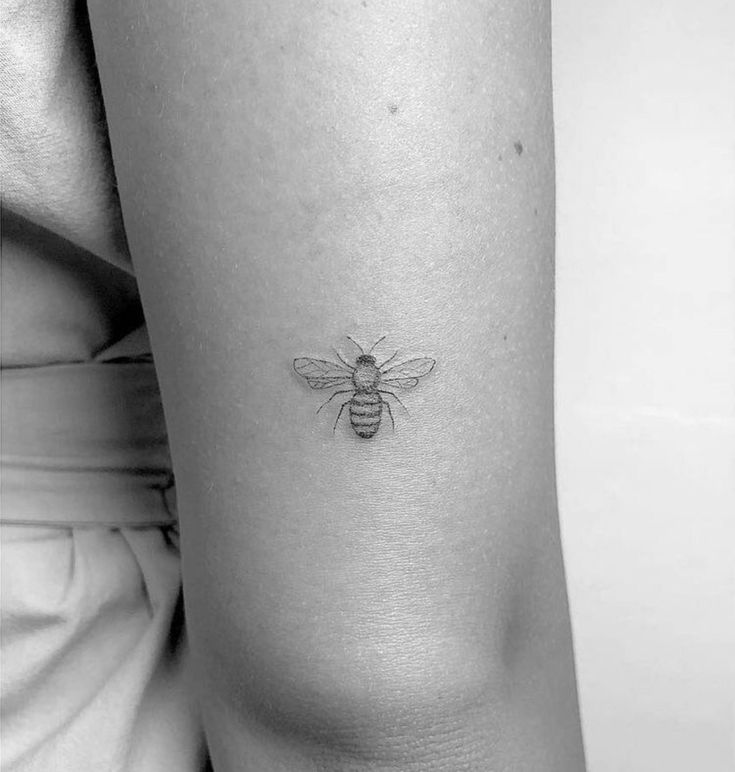 a small bee tattoo on the right side of the thigh, it is black and white