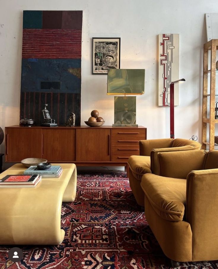 a living room filled with lots of furniture and art on the wall above it's coffee table