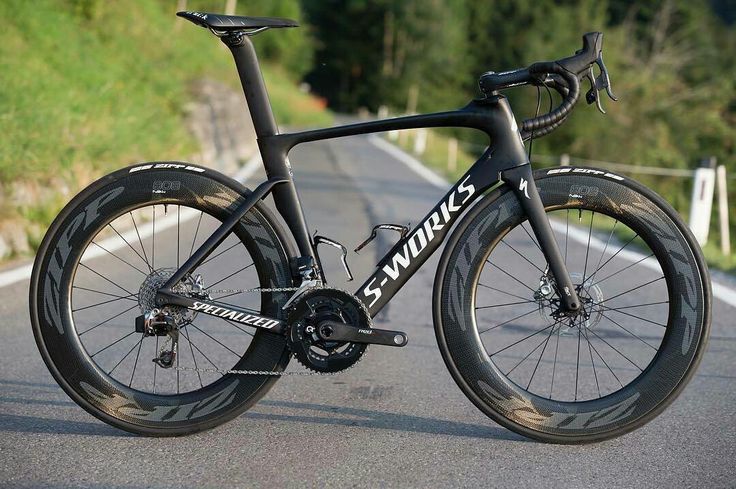 a close up of a bike on a road with grass and trees in the background