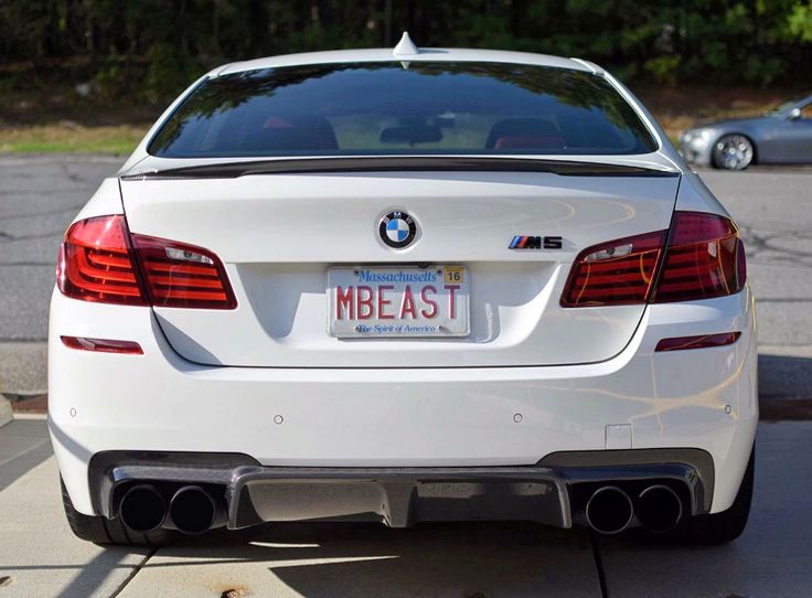 the back end of a white car parked in a parking lot