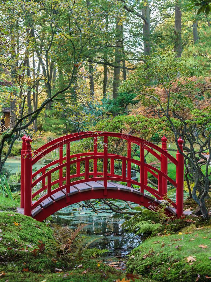 a red bridge over a small pond in a japanese garden