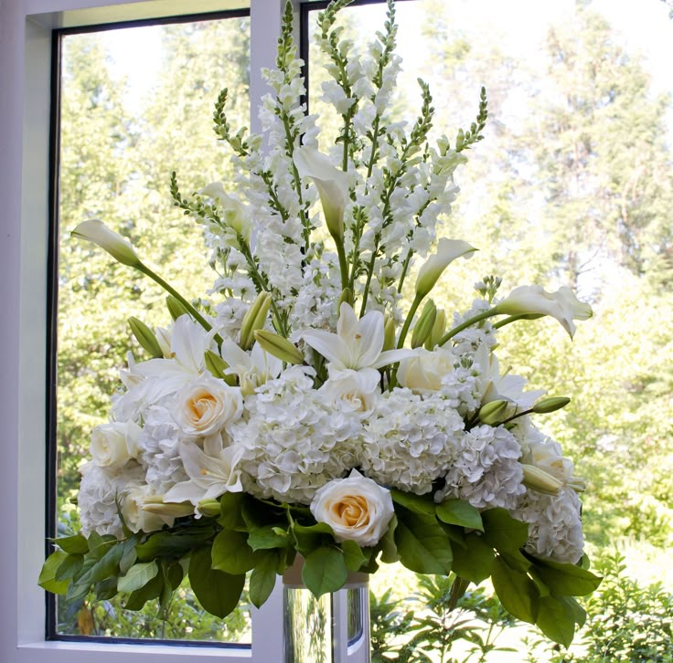 a vase filled with white flowers next to a window