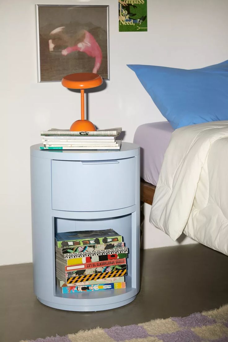 a nightstand with magazines on it next to a bed