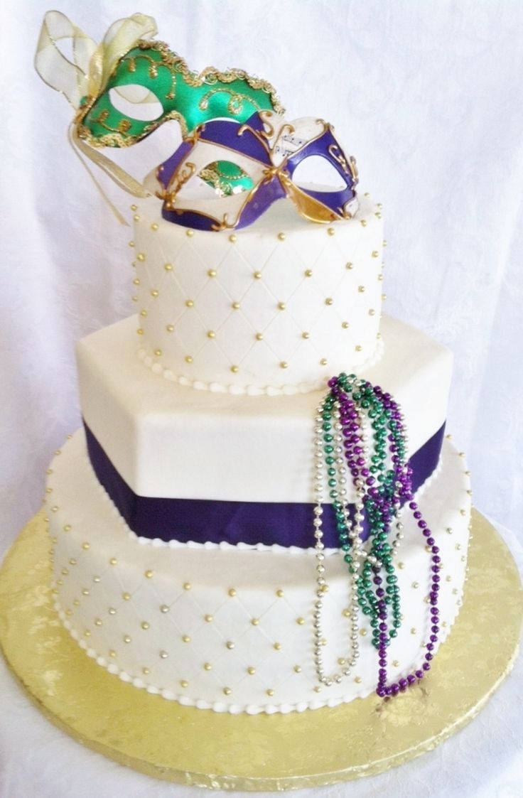 a three tiered cake decorated with mardi gras masks and beads on top