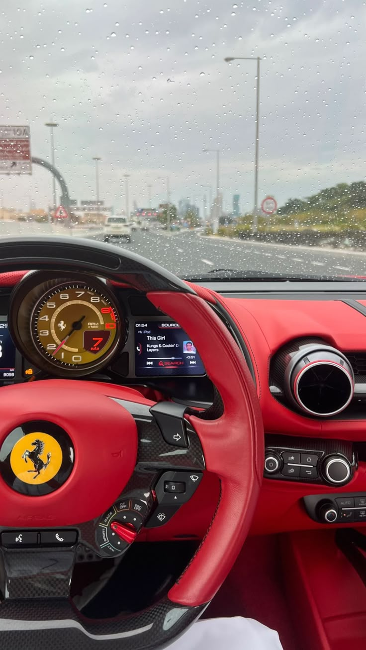 the interior of a red sports car with steering wheel controls and dashboard gauges on