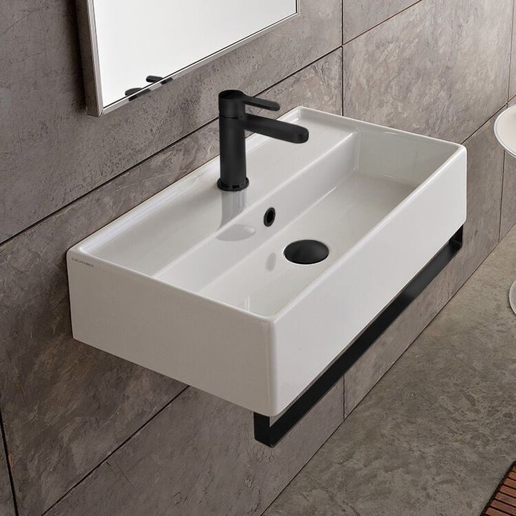 a white sink sitting next to a mirror in a bathroom under a faucet